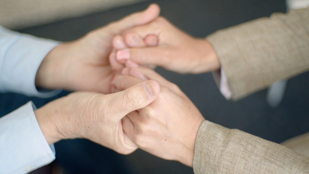A heartfelt close-up showing a couple holding hands, symbolizing support and togetherness.